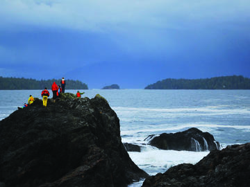 A group of people atop a rock next to the ocean.