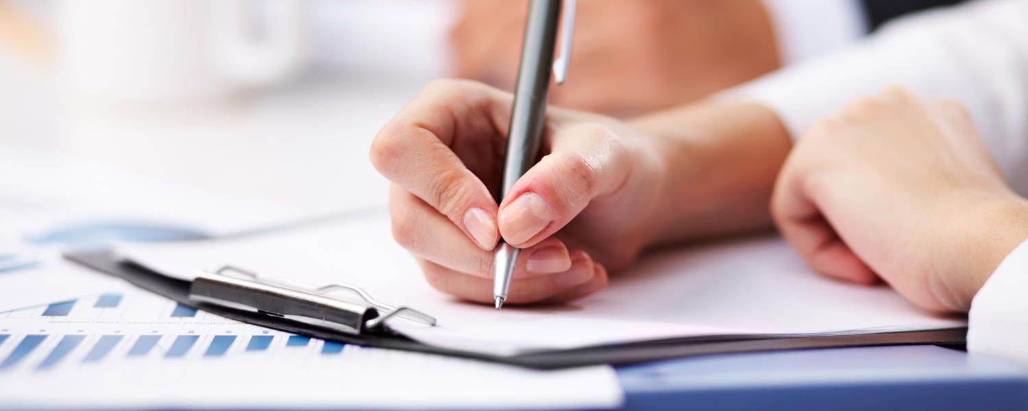 Person writing on a clipboard