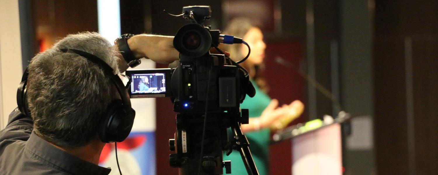 Man recording a speaker with a camera