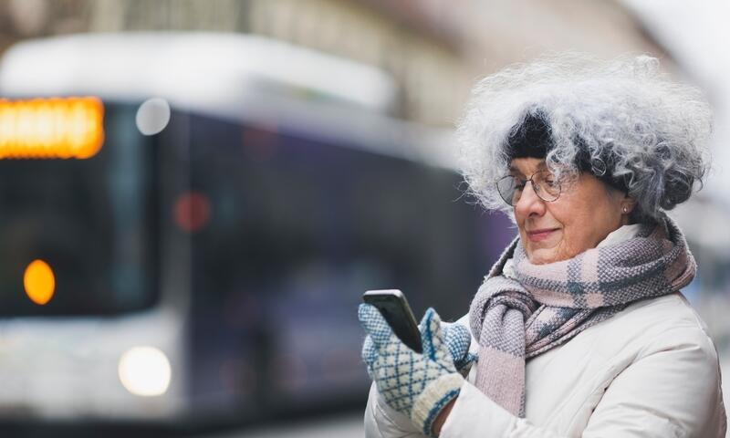 Older woman on her phone, waiting for transit