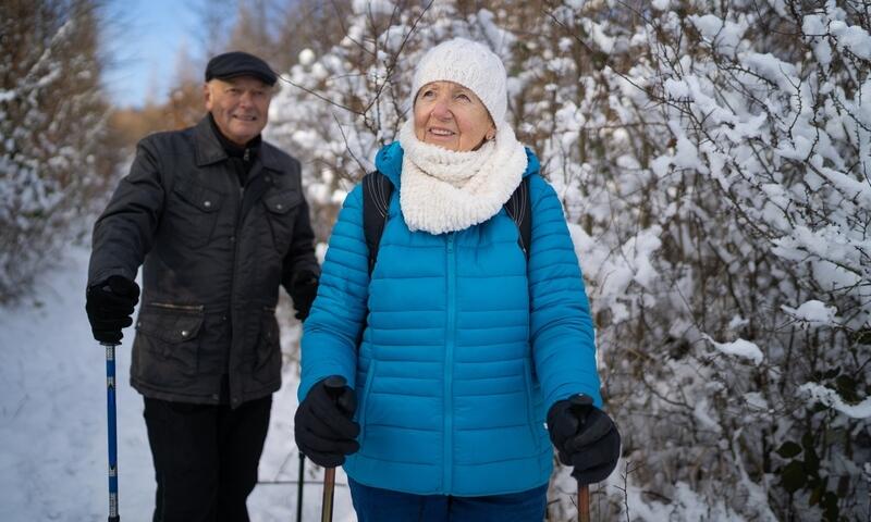 An older woman and older man walking in winter with poles