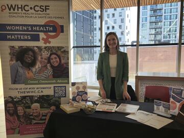Woman at booth at the Calgary Women's Health Symposium 2025