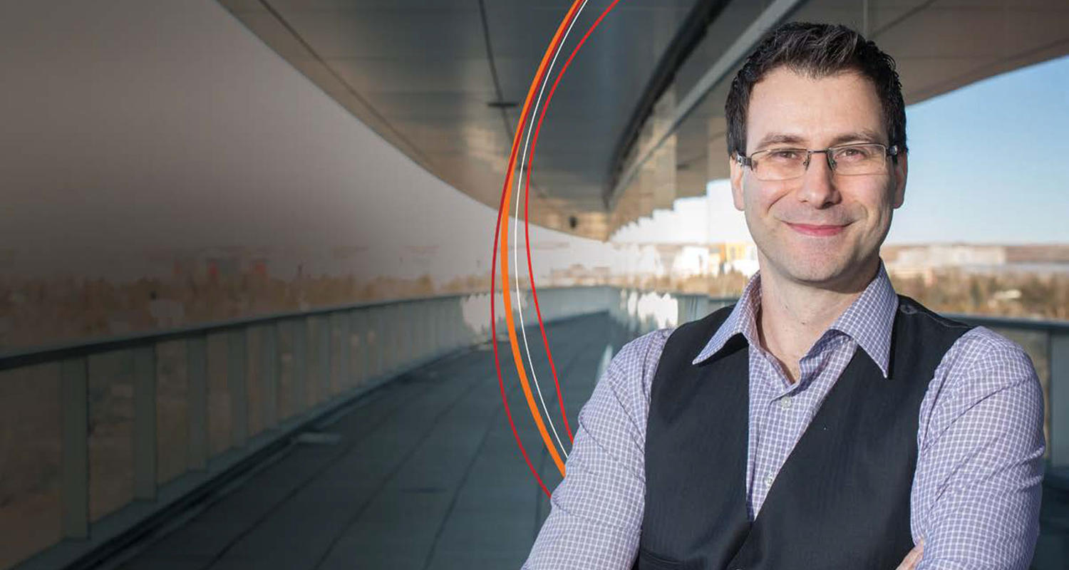 Man standing in glass hallway with orange, red, and white curves behind him.