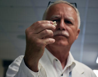 Researcher looking at a pill 